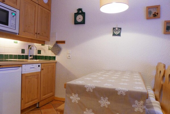 Eine Küche mit Holzausstattung, einer Mikrowelle, einem Spülbecken und einem Tisch mit einem Tischläufer mit Schneeflockenmuster.