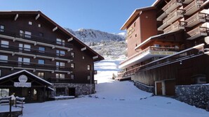 Un hotel cubierto de nieve con varios balcones y un paisaje de montañas.