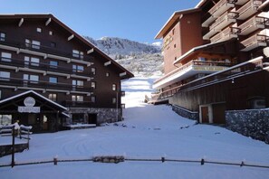 Ett snötäckt hotell med flera balkonger och en bergskedja i bakgrunden.