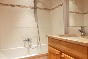 Ein Badezimmer mit Badewanne, Dusche und Waschtisch mit Spiegel.