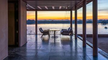 Relax in a serene outdoor seating area with a breathtaking view of the water and distant mountains.