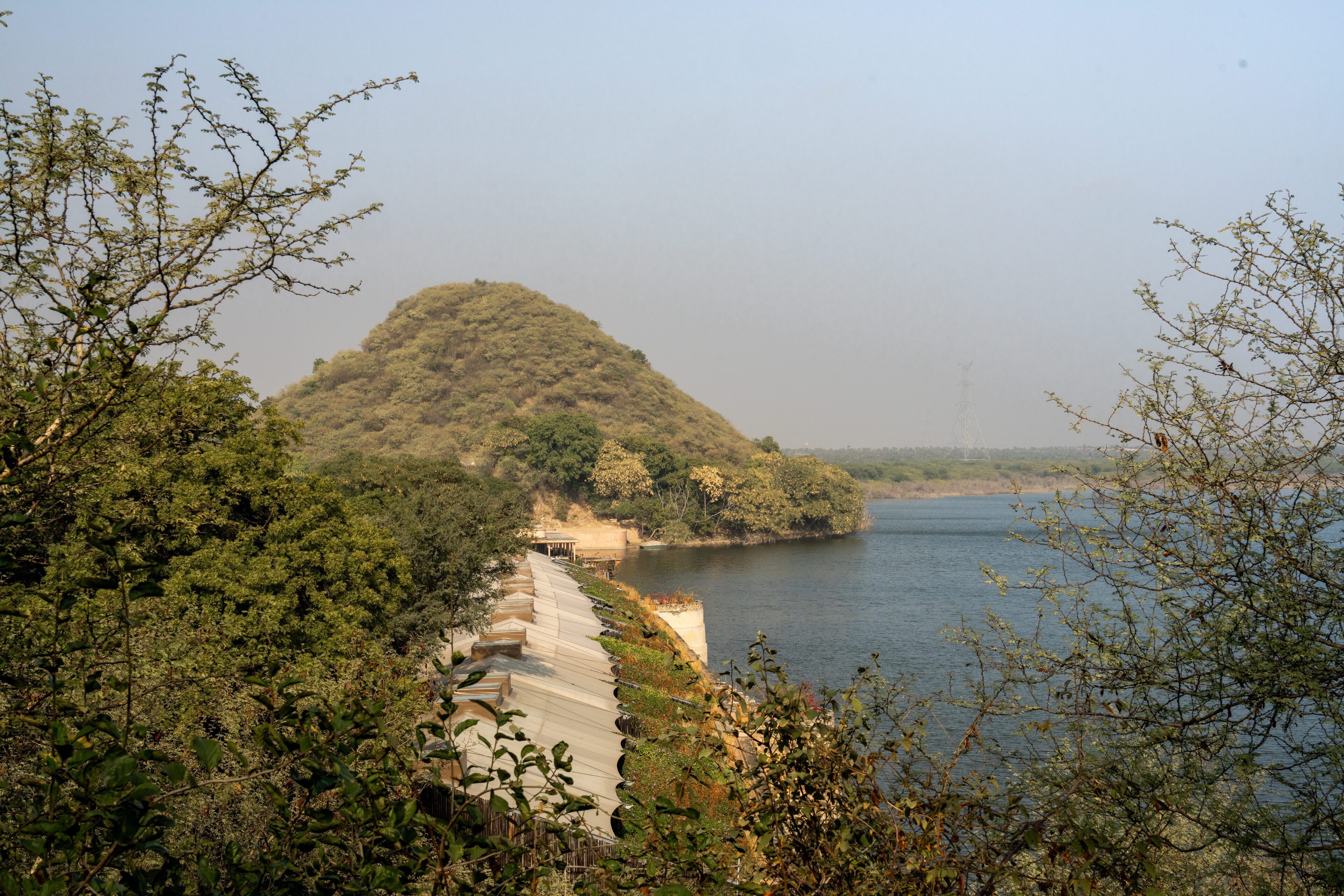 A riverbank with a concrete walkway and a hill in the background.