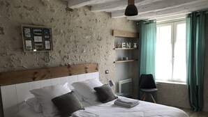 A bedroom with a bed, pillows, a nightstand, a wall-mounted bulletin board, and a window with curtains. - Gite l'Hermine, 15 pers, heated indoor pool, RDC PMR, enclosed garden (Azay-le-Rideau)