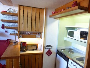 A compact kitchen with wooden cabinets, a microwave, and a stove.