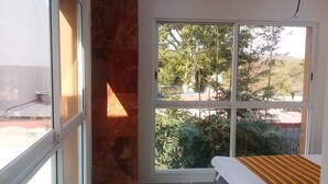 Un dormitorio con un ventanal grande, una cama y una pared de acento roja.