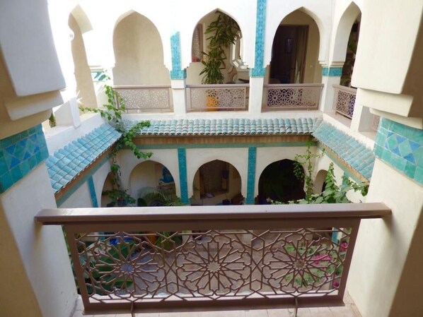 A courtyard with arches, a decorative railing, and tiled flooring.