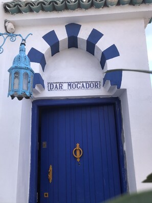 A blue door with a gold knocker and a sign above it that reads "DAR MOGADOR."