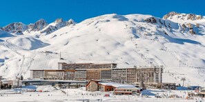 A hotel with multiple floors, ski slopes in the background, and a mountainous landscape. - 10m from resort center, 2nd floor, balcony, tv, ski locker, 28m², Tignes (Tignes)