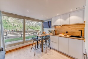 A modern kitchen with a wooden countertop, a sink, and a dining area with a table and chairs.