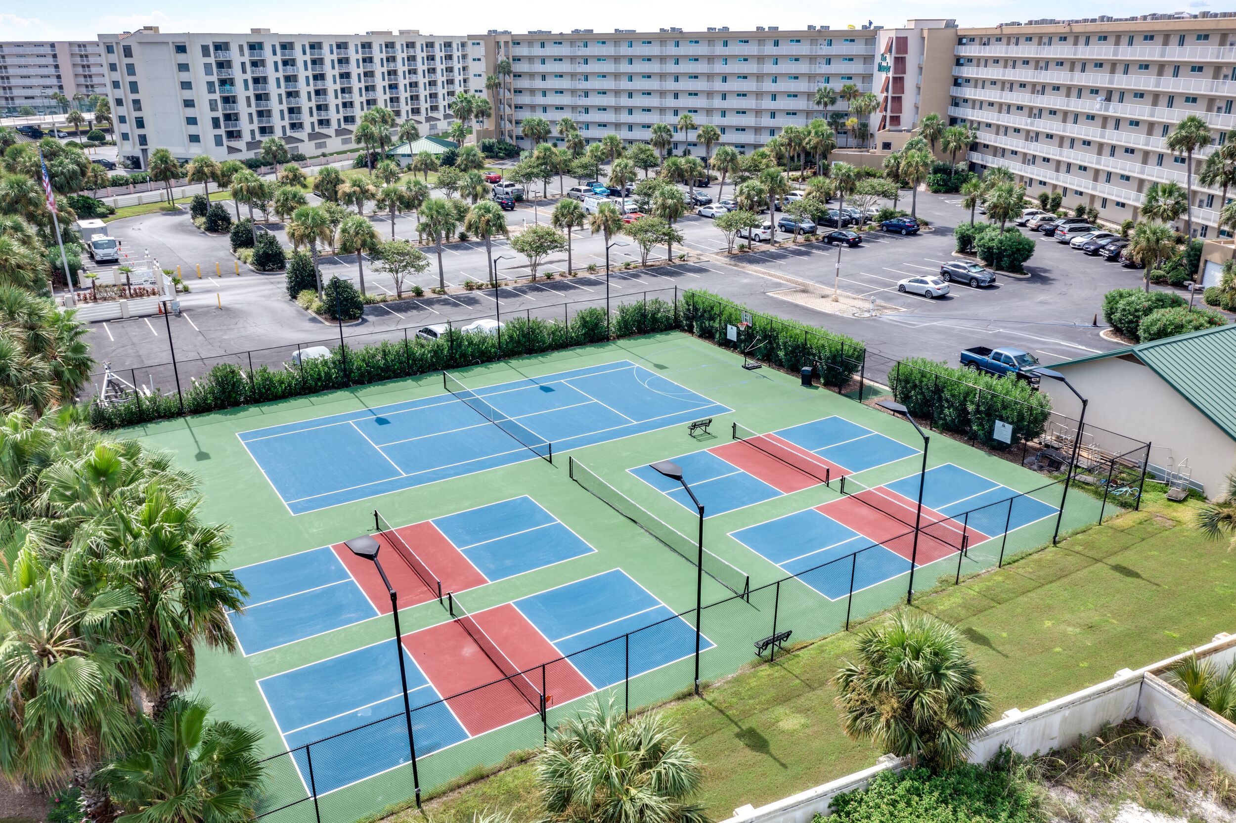 Ein mehrstöckiges Hotel mit Tennisplatz und Parkbereich.