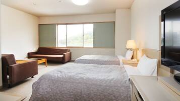 A hotel room with two beds, a sofa, a TV, and a window with a view.