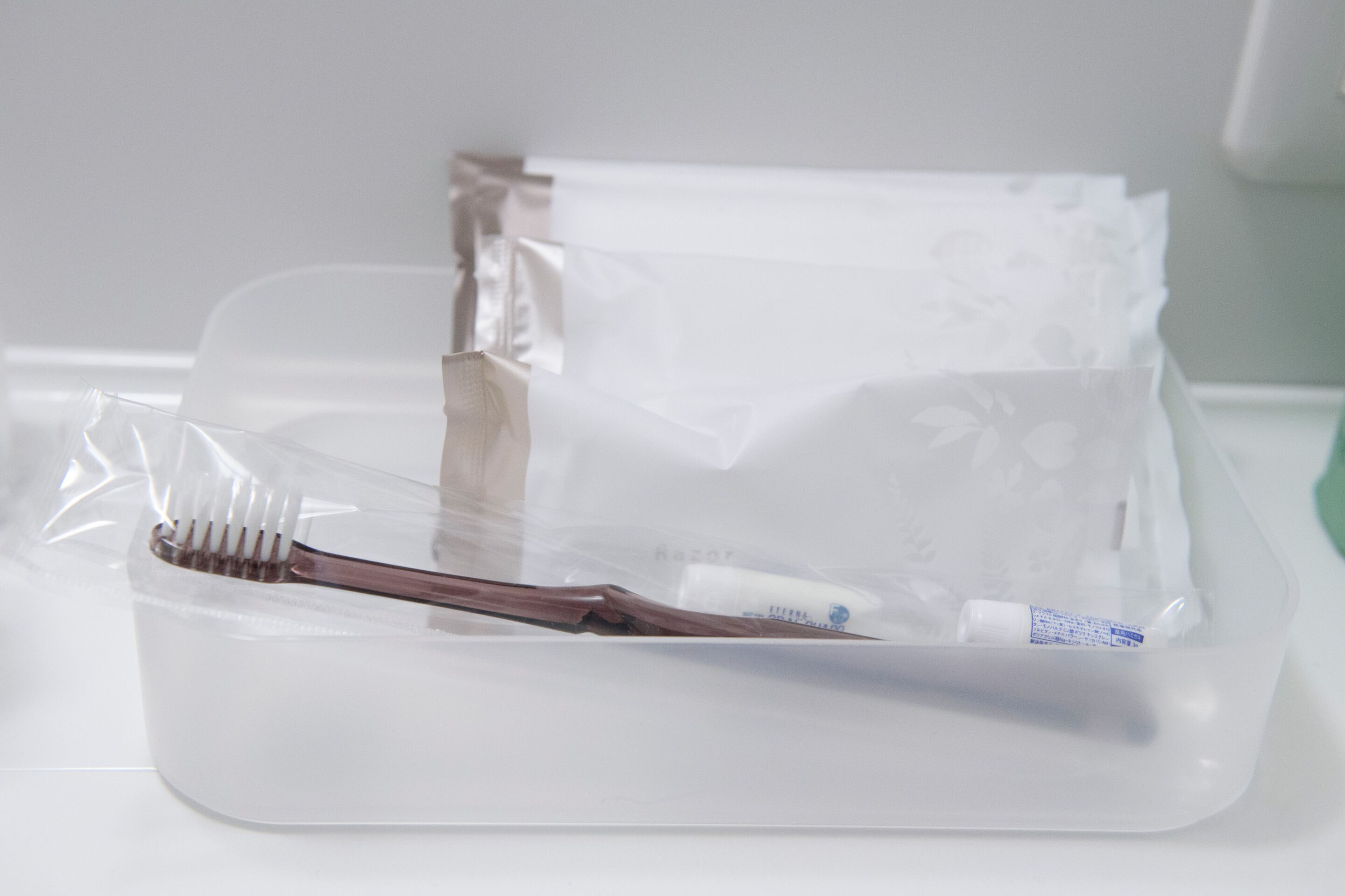 Embalagem transparente de plástico com uma escova de dentes e um tubo, provavelmente contendo artigos de higiene pessoal.