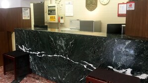 A reception desk with a marble counter, a clock, and a payphone. - Hotel Sports Palko (Gifu)