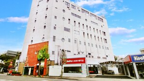 A multi-story building with a white facade, a red-brick entrance, and a visible car wash facility. - Hotel Sports Palko (Gifu)