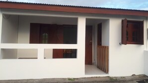 A single-story house with a red roof, a satellite dish, and a wooden door. - Charming cozy house type T3---------------------- (sainte-anne en Guadeloupe)