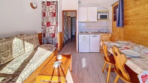 A compact living space with a sofa, dining table, and kitchenette.