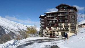 A multi-story hotel with balconies, situated in a snowy mountainous area.