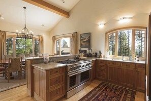 Enjoy cooking in this well-lit kitchen with a large island, stainless steel stove, and ample counter space.