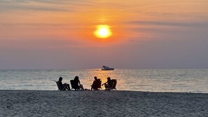 A sunset over the ocean with a boat in the distance and people sitting on beach chairs. - Close to town Large Yard Fire Pit Gas Grill Beach 2.5 blocks (Union Pier)
