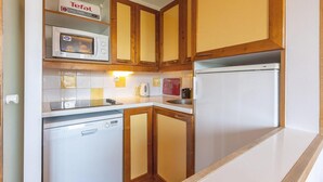Une cuisine compacte dotée de meubles en bois, d’un four à micro-ondes, d’un grille-pain et d’un lave-vaisselle.
