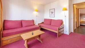 Une pièce chaleureuse avec deux canapés en bois, une petite table en bois et un tableau encadré au mur.