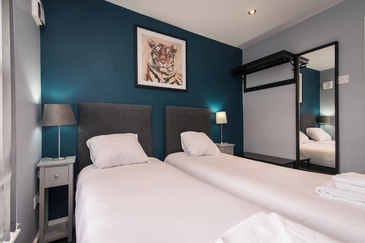 A hotel room with two beds, a large mirror, and a tiger artwork on the wall.