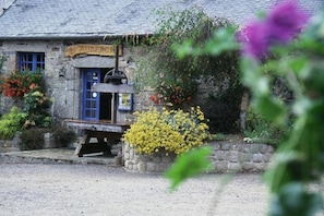 A stone building with a blue door, a sign reading 'AUBERGE,' and a small outdoor seating area. - Cottages, bed and breakfasts in the heart of the North Finistère countryside. (PLOUEGAT MOYSAN)