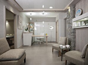 A modern kitchen with white cabinets, a dining table, and chairs. There is a small refrigerator and a sink in the kitchen area.