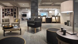 Un salon moderne avec un pilier en pierre, une table basse et des coins salon.