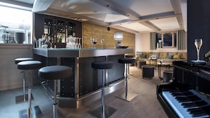Un espace bar moderne avec des tabourets, un piano et un meuble à bouteilles de vin.