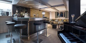 A modern bar area with stools, a piano, and a wine rack.