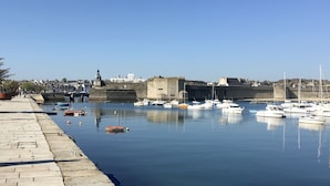 Um porto com barcos atracados, um muro de pedra e um céu limpo.