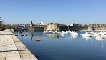 Un port où des bateaux sont amarrés, un mur de pierre et un ciel dégagé.