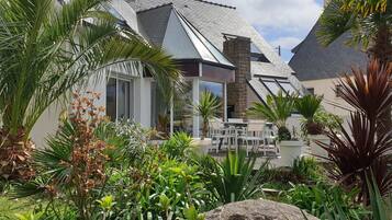 Une maison moderne dotée d’un patio aménagé avec du mobilier d’extérieur et une végétation luxuriante.