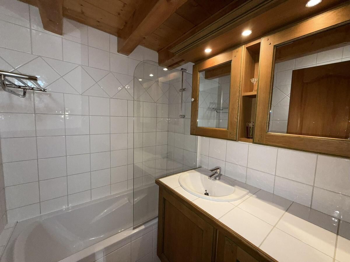 Uma casa de banho moderna com cabine de duche envidraçada, uma sanita branca e armários de madeira.