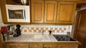 A compact kitchen with wooden cabinets, a white microwave, a sink, and a coffee maker.