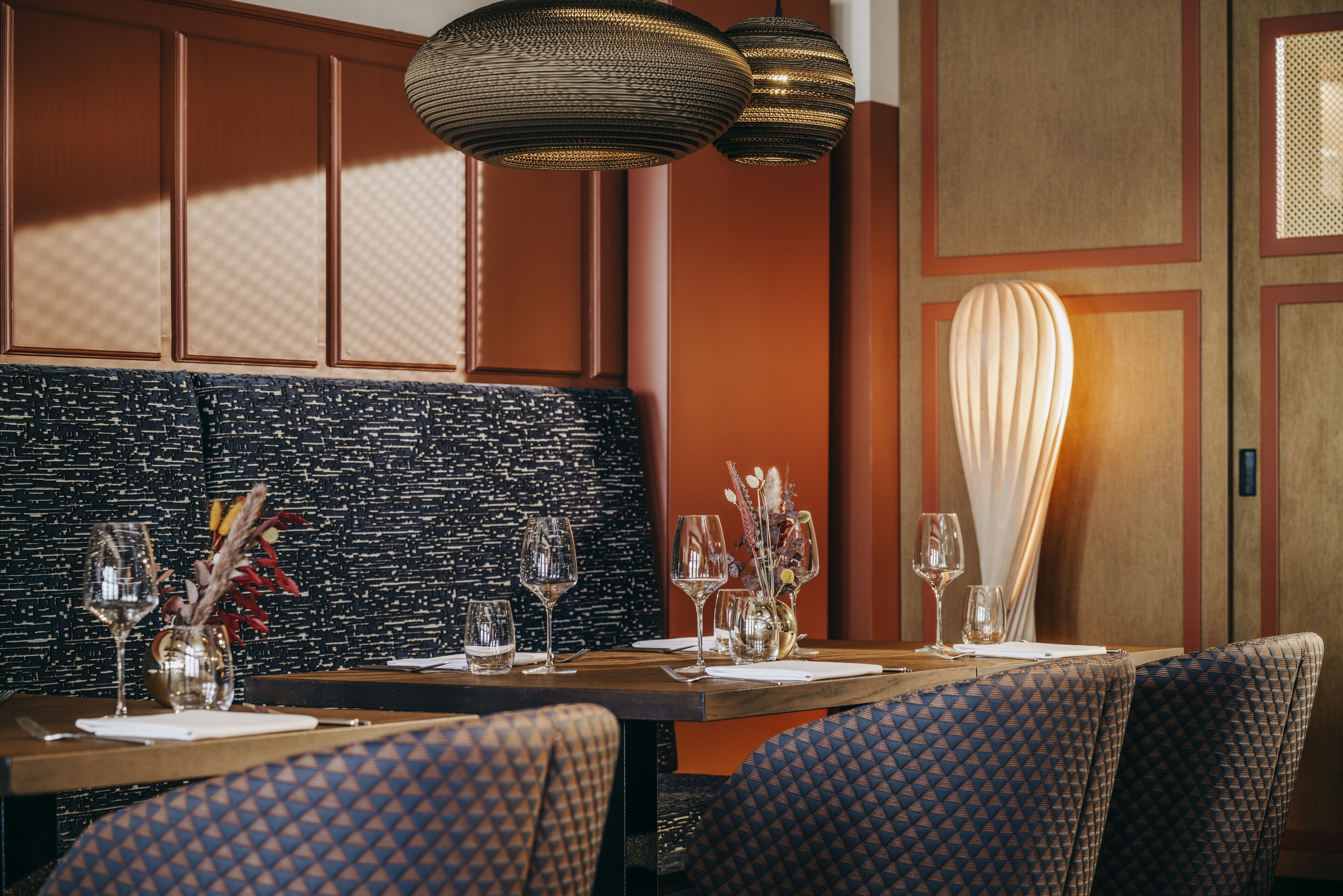 Un comedor con una mesa de madera preparada para cuatro personas, rodeado de sillas estampadas.