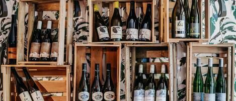 Una colección de cajas de madera llenas de botellas de vino, dispuestas frente a un fondo de papel tapiz estampado.