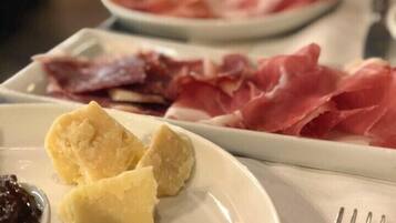 A plate with various food items including cured meats, cheese, and a small bowl of jam.