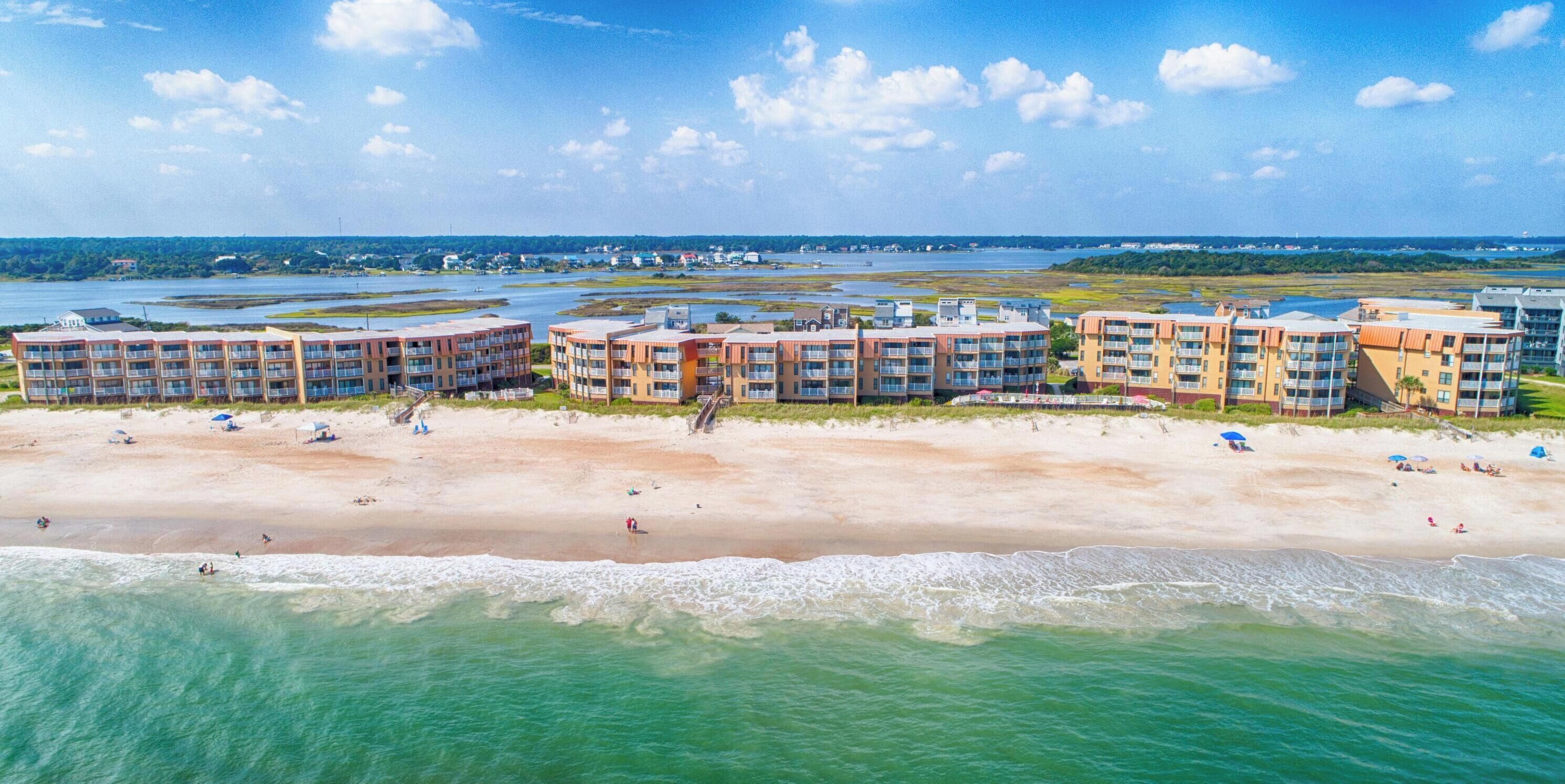 A beachfront hotel with multiple buildings, a sandy beach, and a view of the ocean.