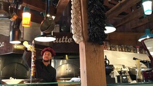 En restaurantindretning med træloft, hængende lys og et skilt der viser menuer.