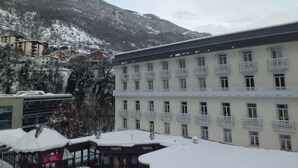 A hotel with multiple floors, balconies, and a mountainous backdrop.