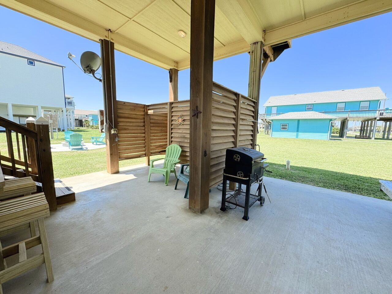 A covered patio area with wooden beams, a grill, and outdoor chairs.