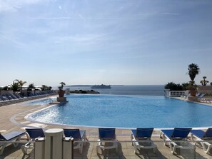 A swimming pool with lounge chairs and a view of the sea. - T2 superb apart with sea view at Cannes (Cannes La Bocca)