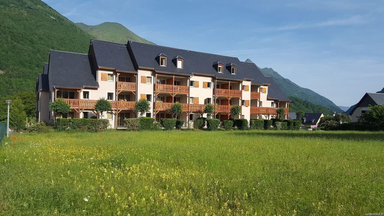 Un hôtel à plusieurs étages, doté de balcons, situé dans un cadre montagneux.