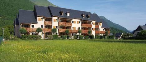Un hôtel à plusieurs étages, doté de balcons, situé dans un cadre montagneux.
