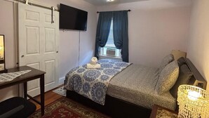 A bedroom with a bed, a desk, a chair, a ceiling fan, a television, and a window with curtains. - 2BR-Free Parking, Near Gillette & Providence-I-95 (Pawtucket)