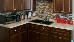 Una cocina con armarios de madera, un microondas negro, un lavamanos y un ventilador de techo.
