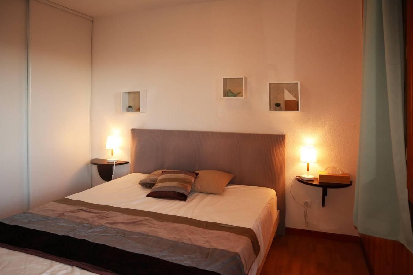 Une chambre d’hôtel comprenant un lit, des tables de chevet, des lampes et des œuvres d’art accrochées au mur.