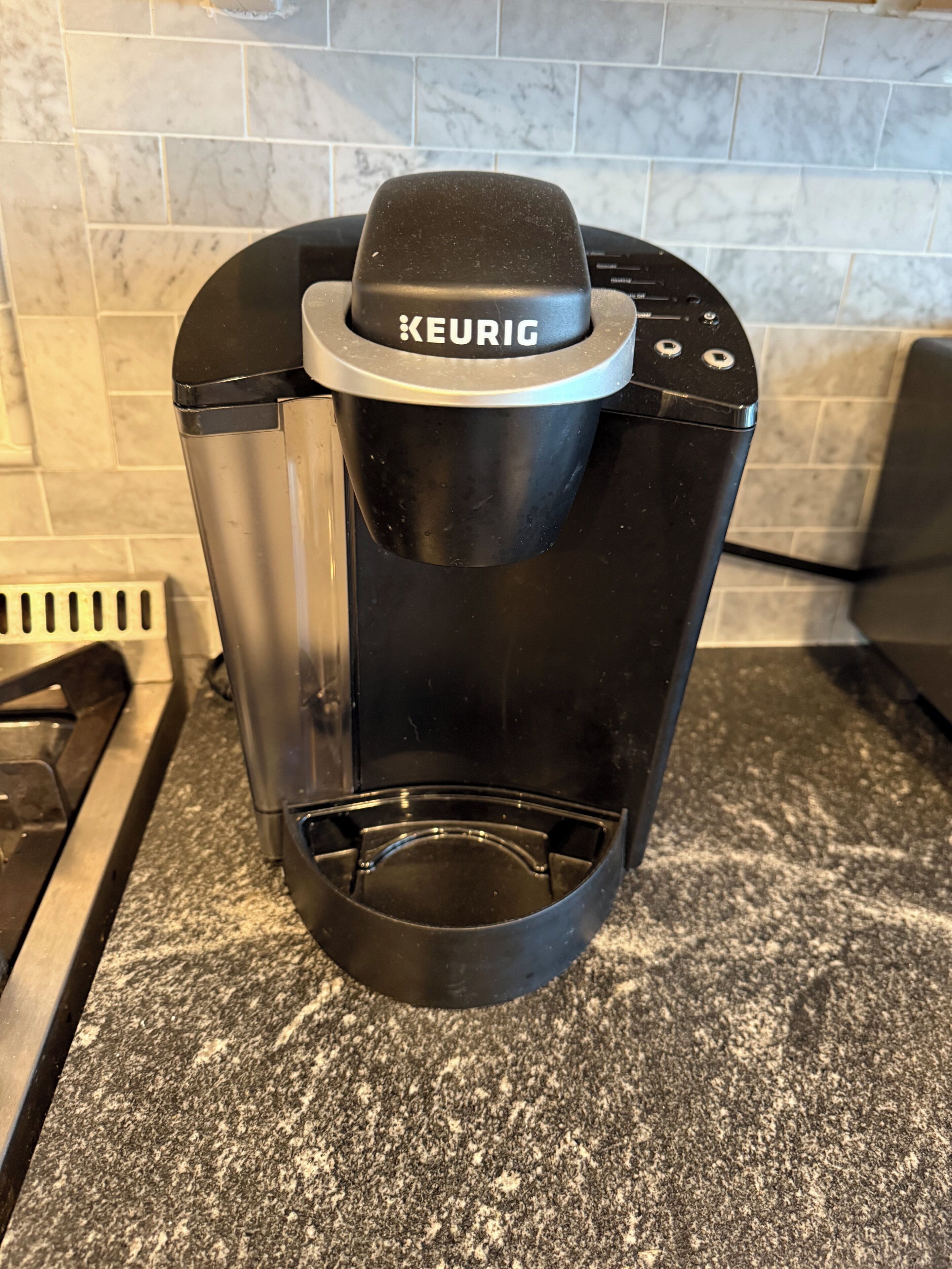 En svart Keurig-kaffebryggare står på en bänkskiva av granit.
